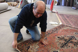 Mohammad Rafatpanah analyzing an antique oriental rug for an appraisal.