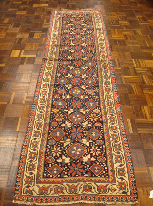 An antique Caucasian runner with large worm areas after repair.