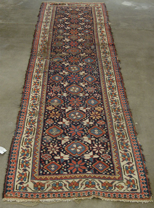 An antique Caucasian runner with large worm areas before repair.