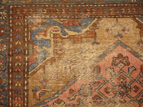 An antique Caucasian carpet with large worm areas before repair.