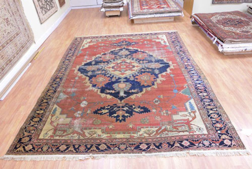 An antique Persian Serapi with large worm areas before repair.