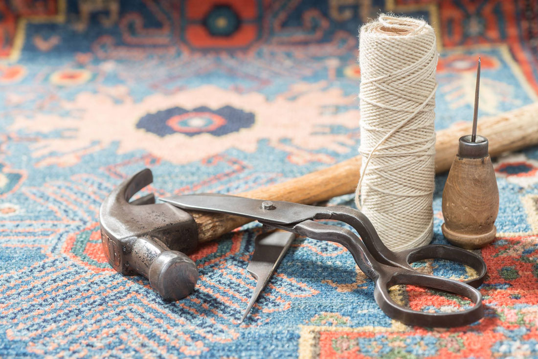 An elegant arrangement of oriental rug repair tools placed on an antique Persian rug.