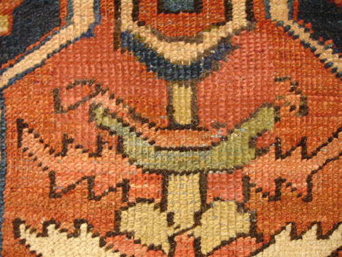 An antique Persian Heriz carpet with moth damage after repair.