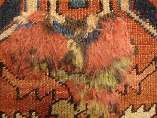 An antique Persian Heriz carpet with moth damage during repair.