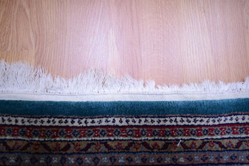 An oriental rug with damaged fringe before repair.