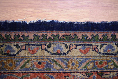An oriental rug with damaged sides before repair.